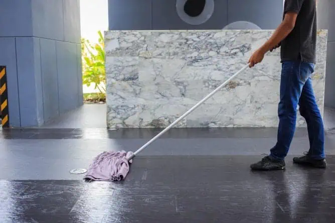 A person mopping floor of a Stone Restoration Company easily.